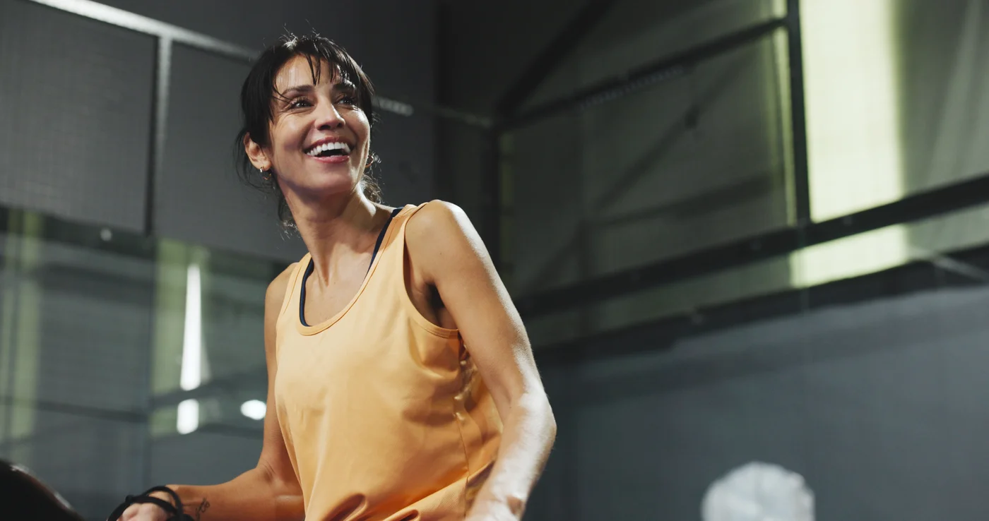 Joueuse de padel souriante sur terrain couvert — Élite Padel Lille