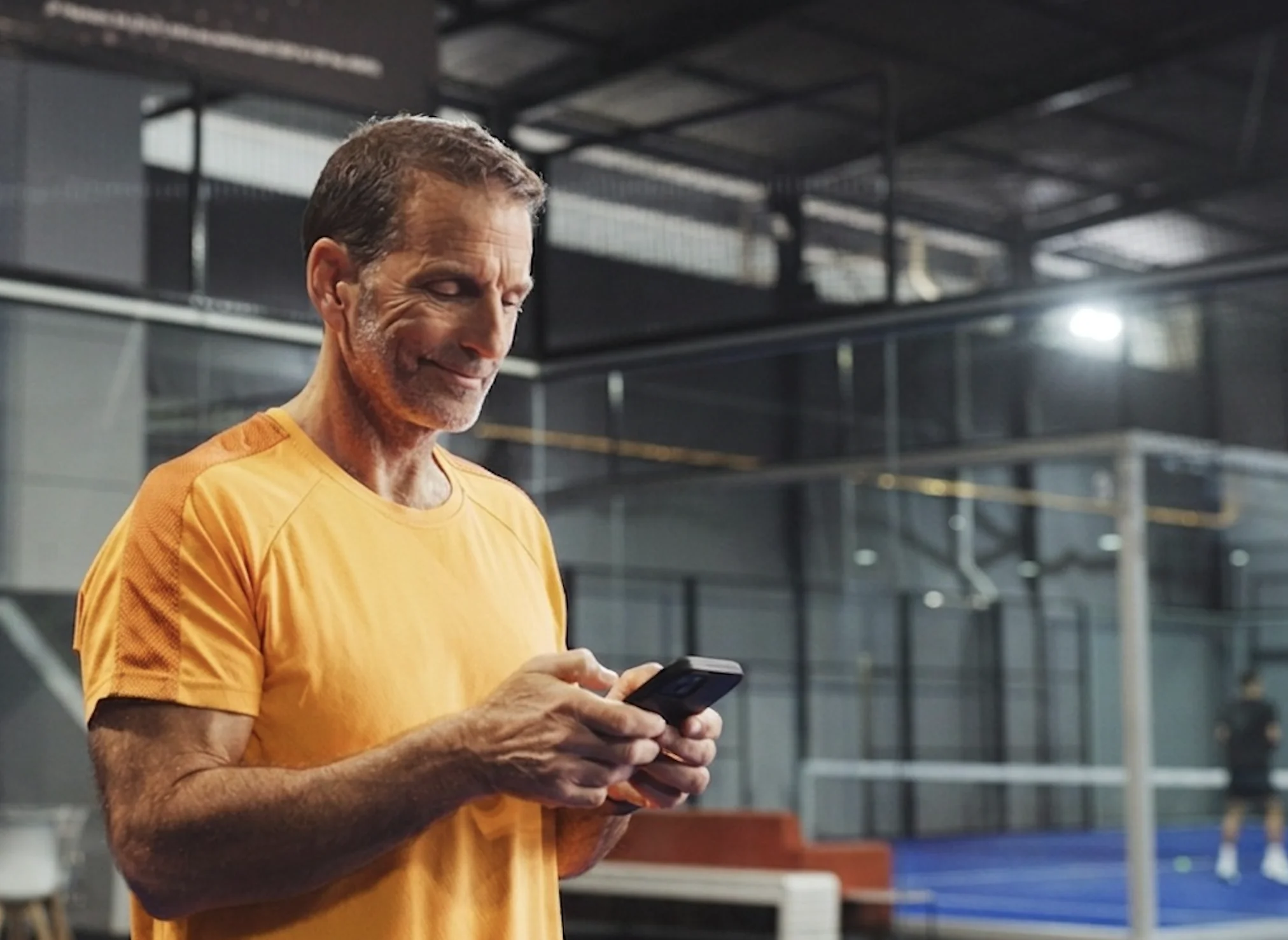 Joueur de padel consultant son téléphone dans une salle de padel — Élite Padel Lille